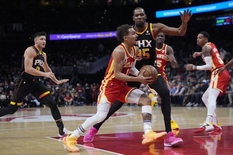 CORRECTS ID TO TRAE YOUNG - Atlanta Hawks guard Trae Young (11) drives againsty Phoenix Suns forward Kevin Durant (35) in the first half of an NBA basketball game Friday, Feb. 2, 2024, in Atlanta. (AP Photo/John Bazemore)