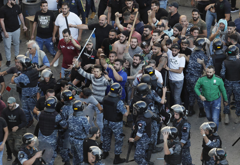 FILE - In this Oct. 29, 2019 file photo, riot police try to stop supporters of the Shiite Hezbollah group who arrived to burn and destroy tents in the camp set up by anti-government protesters near the government palace, in Beirut, Lebanon. Lebanon’s protests have shown unusual overt anger at the country’s powerhouse, Hezbollah. (AP Photo/Hussein Malla, File)