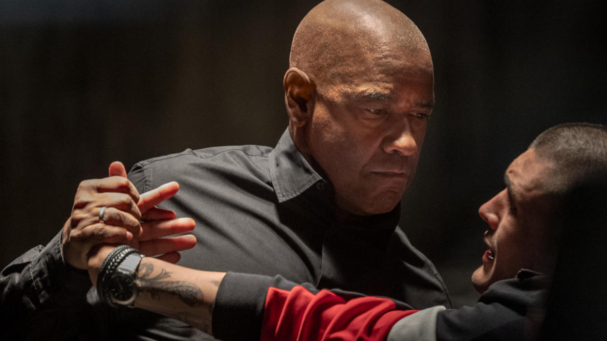  Denzel Washington bends a man's wrist with a menacing face in The Equalizer 3. 