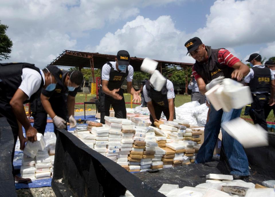 Dominican Republic police officers toss packages of cocaine to be burned at a military base in Santo Domingo, Wednesday, Aug. 5, 2009. At least 2,800 lbs (1,270 kilogram) of cocaine, marijuana and heroin were destroyed after being confiscated by the Dominican anti-drugs agency. (AP Photo/Kena Betancur)