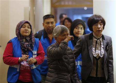 A relative (C) of a passenger aboard Malaysia Airlines MH370 reacts as she enters a meeting room with volunteers from Malaysia (in blue vests) at the Lido Hotel in Beijing March 27, 2014. REUTERS/Kim Kyung-Hoon