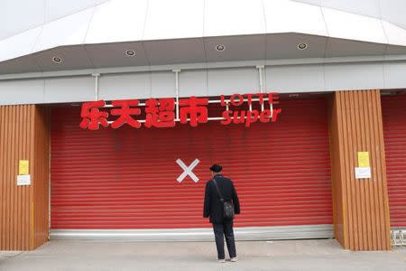 A man stands outside a closed Lotte Super in Beijing, China March 17, 2017. Picture taken March 17, 2017. REUTERS/Stringer