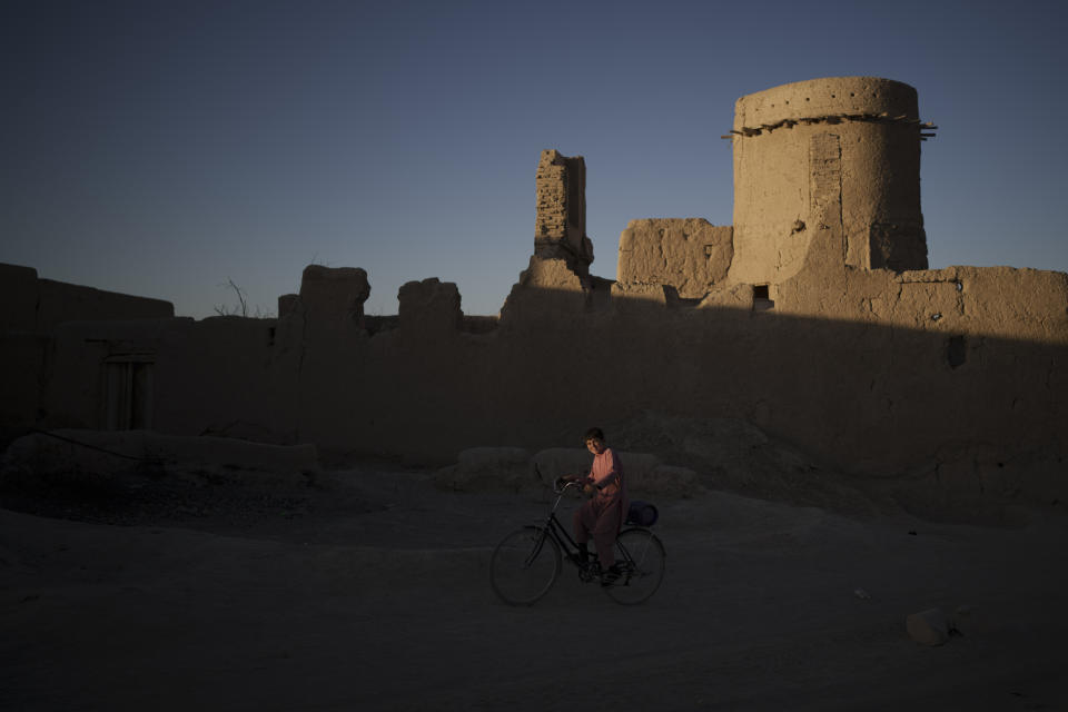 A boy rides his bicycle as the sun sets at a village in Wardak province, Afghanistan, Tuesday, Oct. 12, 2021. (AP Photo/Felipe Dana)