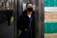 A man wearing a face mask looks at a board at a bus stop, as the country is hit by an outbreak of the new coronavirus, in Beijing