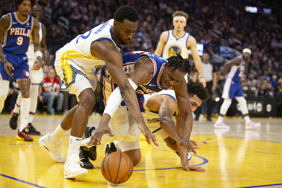 Philadelphia 76ers forward Danuel House Jr., center, battles Golden State Warriors forwards Andrew Wiggins (22) and Trayce Jackson-Davis, right, for possession during the first half of an NBA basketball game, Tuesday, Jan. 30, 2024, in San Francisco. (AP Photo/D. Ross Cameron)
