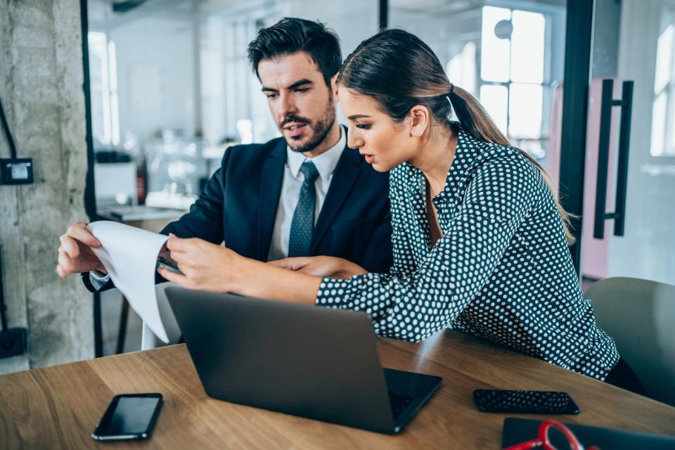 Two investors study something in front of a laptop.