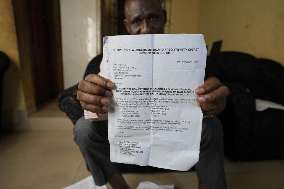Pius Orofin, a deck operator aboard the Trinity Spirit oil ship, holds up a document listing non-payment and other complaints by crew members of the Trinity Spirit, during an interview at his home in Okitipupa, Nigeria, on Tuesday, Sept. 6, 2022. The Trinity Spirit was among a global fleet of what's known in the oil exploration industry as floating production storage and offloading units, commonly referred to by the acronym FPSOs. The ships are connected to wells at sea and separate crude oil from water before oil is offloaded and transferred for further refining. (AP Photo/Sunday Alamba)