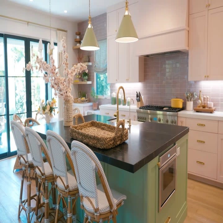 The kitchen has a large glass double door to let in some natural lighting and the green island stands out in the room