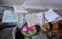 Messages wishing safe return of passengers aboard the sunken ferry Sewol hang with a Buddhism lotus decoration in Jindo, south of Seoul, South Korea, Tuesday, April 22, 2014. One by one, coast guard officers carried the newly arrived bodies covered in white sheets from a boat to a tent on the dock of this island, the first step in identifying a sharply rising number of corpses from a South Korean ferry that sank nearly a week ago. (AP Photo/Lee Jin-man)