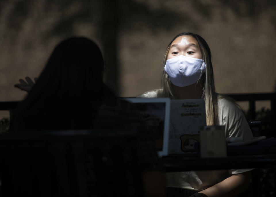 Junior chemistry major Tiffany Truong speaks with a classmate while sitting outside of the University Center on campus at UTC on Monday, Aug. 17, 2020 in Chattanooga, Tenn. Monday was UTC's first day of classes in person classes since March, when all University of Tennessee schools moved to virtual classes in an effort to stop the spread of COVID-19. (Troy Stolt /Chattanooga Times Free Press via AP)