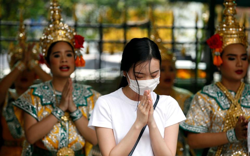 A worshipper wearing protective mask offers prayers in Bangkok after Thai health official confirmed its found two cases of coronavirus - REX