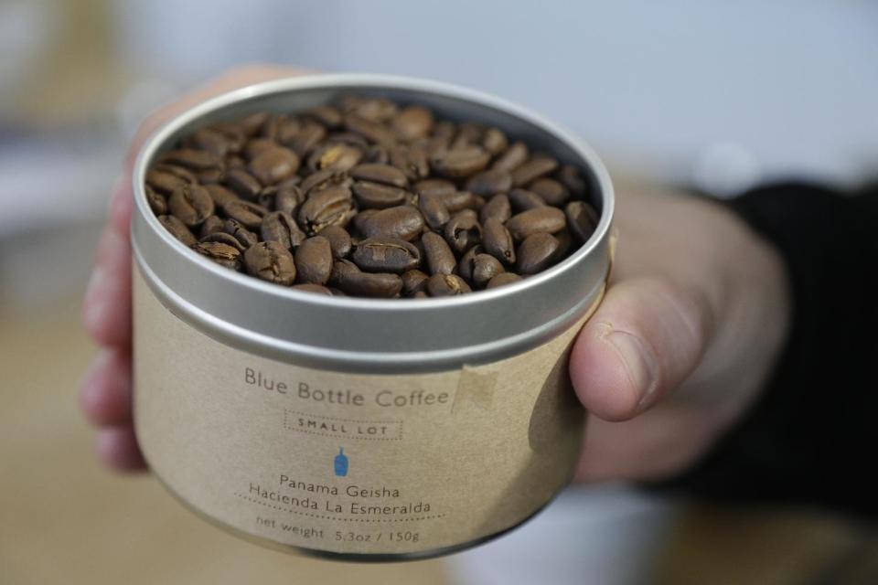 In this photo taken Thursday, Jan. 3, 2013, James Freeman, founder of Blue Bottle Coffee holds a container of Panama Geisha coffee beans at his roastery in Oakland, Calif. (AP Photo/Eric Risberg)