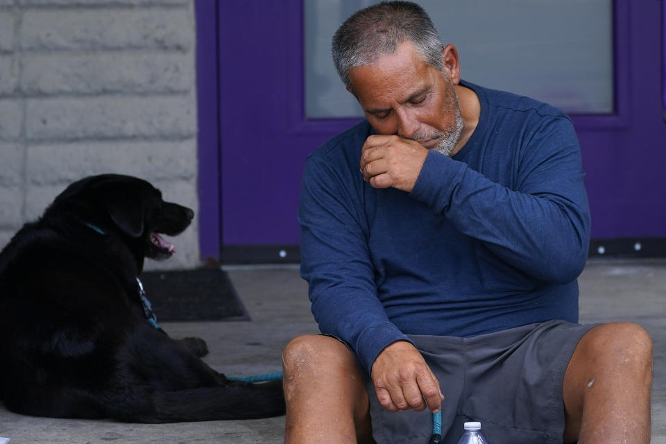 Martin Brown and his dog Sammy try to keep cool outside the Circle In The City homeless clinic, Monday, July 10, 2023, in Phoenix. (AP Photo/Matt York)