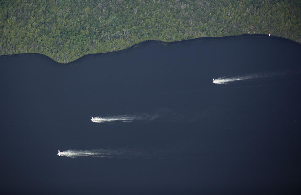 Aircrafts scoop up water from Sand Lake to drop onto the nearby Greenwood Fire, about 50 miles north of Duluth, Minn., Tuesday, Aug. 17, 2021, as seen from an airplane above the temporary flight restriction zone. (Alex Korman/Star Tribune via AP)