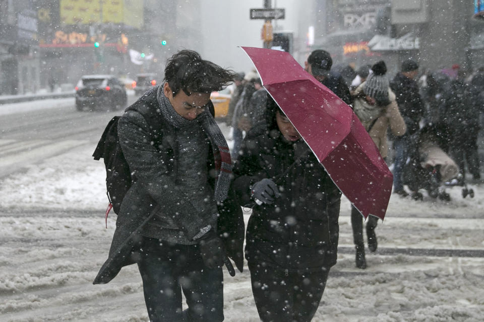 <p>Pedestrians use an umbrella as a shield against high winds and snow as they cross the street in Times Square, Feb. 9, 2017, in New York. (Gordon Donovan/Yahoo News) </p>