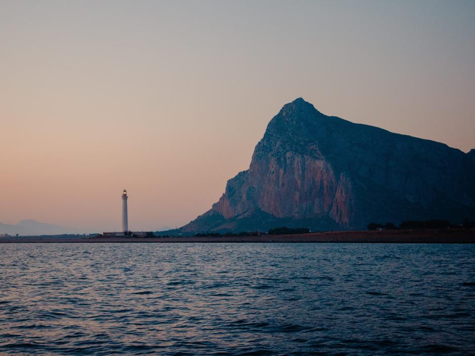 A lighthouse visible in the distance from the sailboat.