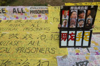 A man holds a poster featuring famous pro-democracy activists outside a court in Hong Kong Monday, March 1, 2021. People gathered outside the court Monday to show support for 47 activists who were detained over the weekend under a new national security law that was imposed on the city by Beijing last year. (AP Photo/Vincent Yu)