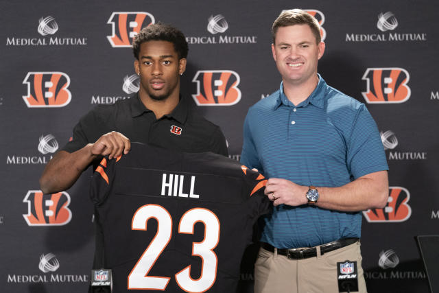 Cincinnati Bengal Daxton Hill holds up a team jersey for a photo