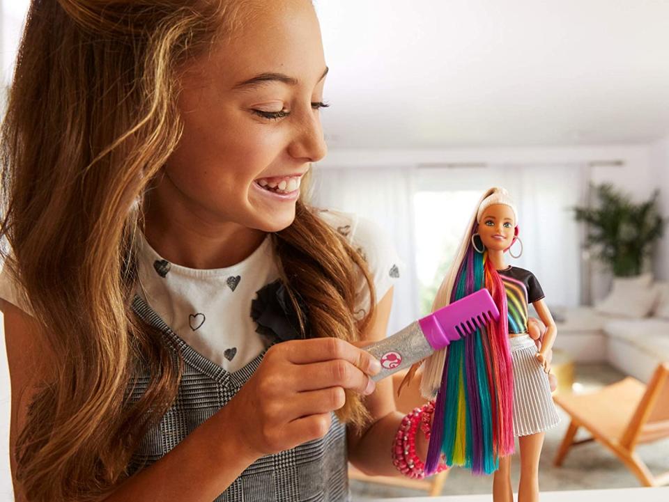Mädchen spielt mit einer Regenbogen-Barbie 