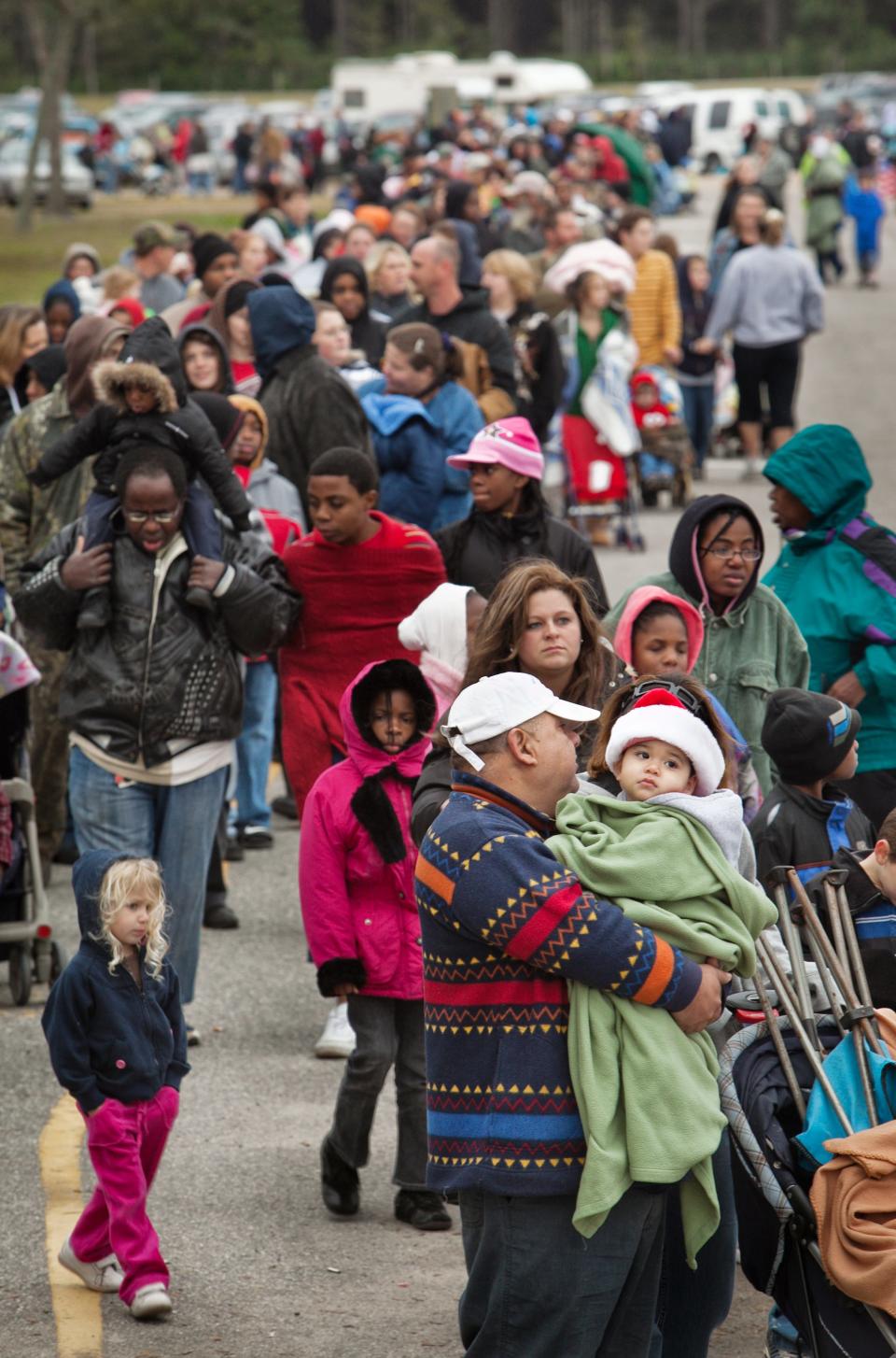 Thousands, including Fernando Villavicencio and his 1-year-old son Yull (bottom, right), stand in line for the J.P. Hall Sr. Children's Christmas Party at the Clay County Fairgrounds in Green Cove Springs in 2009.