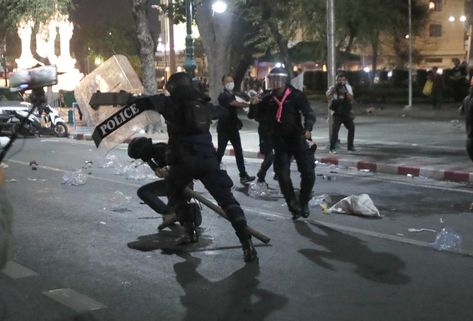 A riot policeman advances towards a man kneeling on the road after the dispersal of protesters who removed container vans used as a barricade in front of the Grand Palace Saturday, March 20, 2021 in Bangkok, Thailand. Thailand's student-led pro-democracy movement is holding a rally in the Thai capital, seeking to press demands that include freedom for their leaders, who are being held without bail on charges of defaming the monarchy. (AP Photo/Sakchai Lalit)