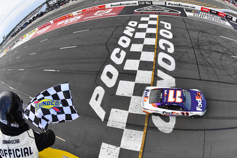 LONG POND, PENNSYLVANIA - JULY 24: Denny Hamlin, driver of the #11 FedEx Office Toyota, takes the checkered flag to win the NASCAR Cup Series M&M's Fan Appreciation 400 at Pocono Raceway on July 24, 2022 in Long Pond, Pennsylvania. (Photo by Logan Riely/Getty Images)