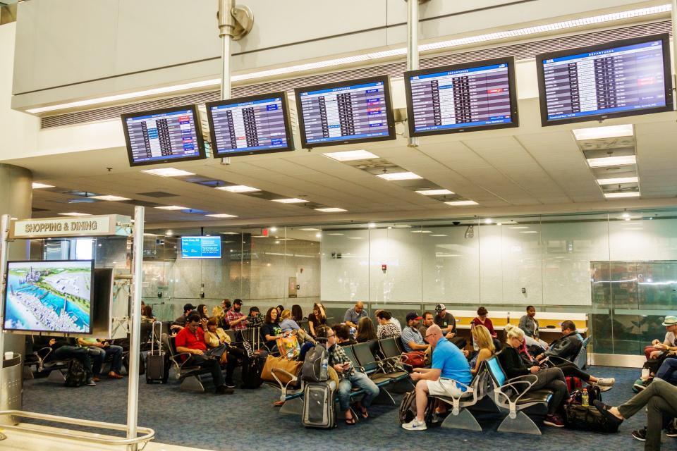 A crowded gate area with a flight information display at Miami International Airport in Florida on March 1, 2018.