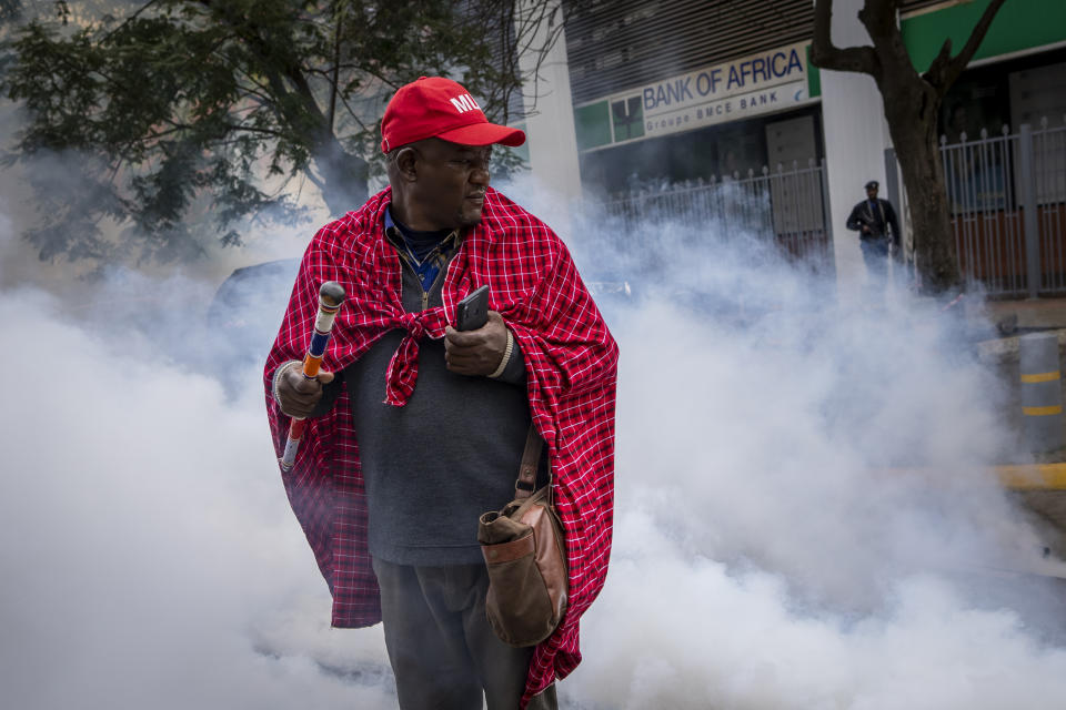 Jonathan Mpute ole Pasha, national coordinator of the Maa Unity Agenda group, is surrounded by tear gas thrown by police to break up a small demonstration of Maasai rights activists outside the Tanzanian high commission in downtown Nairobi, Kenya Friday, June 17, 2022. Tanzania's government is accused of violently trying to evict Maasai herders from one of the country's most popular tourist destinations, the Ngorongoro Conservation Area. (AP Photo/Ben Curtis)