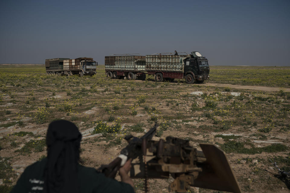 A U.S.-backed Syrian Democratic Forces (SDF) fighter watches as a convoy evacuating hundreds of men, women and children drives out of the last territory held by Islamic State militants, in Baghouz, eastern Syria, Wednesday, Feb. 20, 2019. The evacuation signals the end of a week long standoff and opens the way to U.S.-backed Syrian Democratic Forces (SDF) recapture the territory. (AP Photo/Felipe Dana)