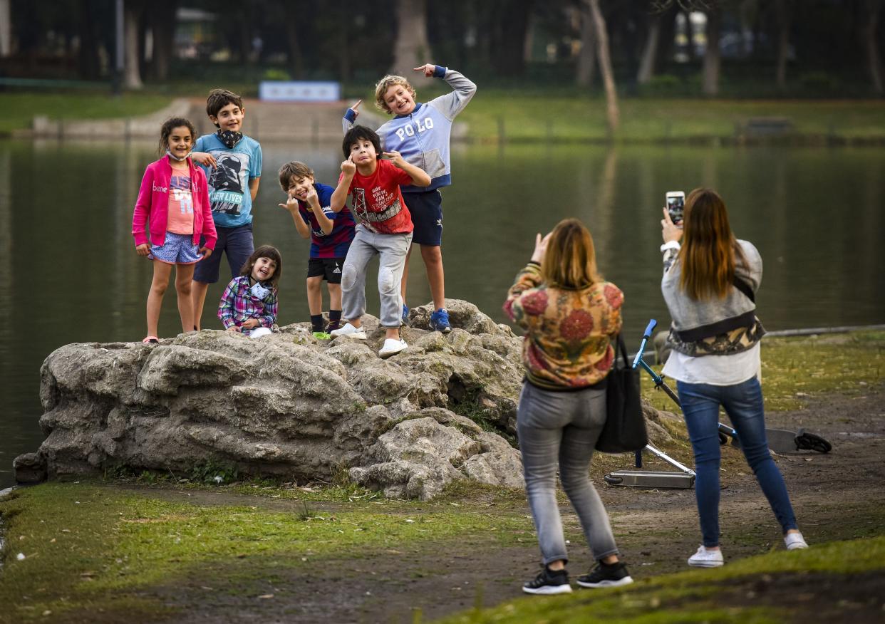 A group of boys pose for a photo by the lake of Palermo on July 20, 2020, in Buenos Aires, Argentina. After the government announced loosening of restrictions, Buenos Aires City starts a new phase of lockdown. Today, non-essential businesses and certain professional activities can restart. Other activities permitted are individual sports, worshiping in temples and take-away restaurants.