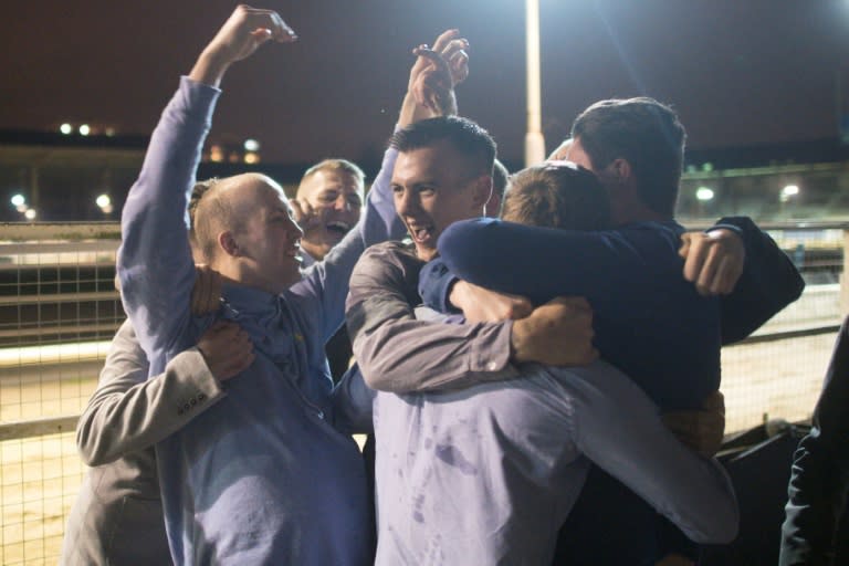 Racegoers celebrate winning a bet during an evening of greyhound racing at the Wimbledon Stadium dog track