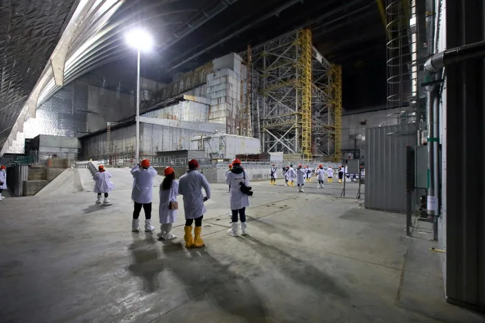 People look at the Object Shelter, also known as the sarcophagus, a temporary structure built in 1986 over the debris at Chernobyl.