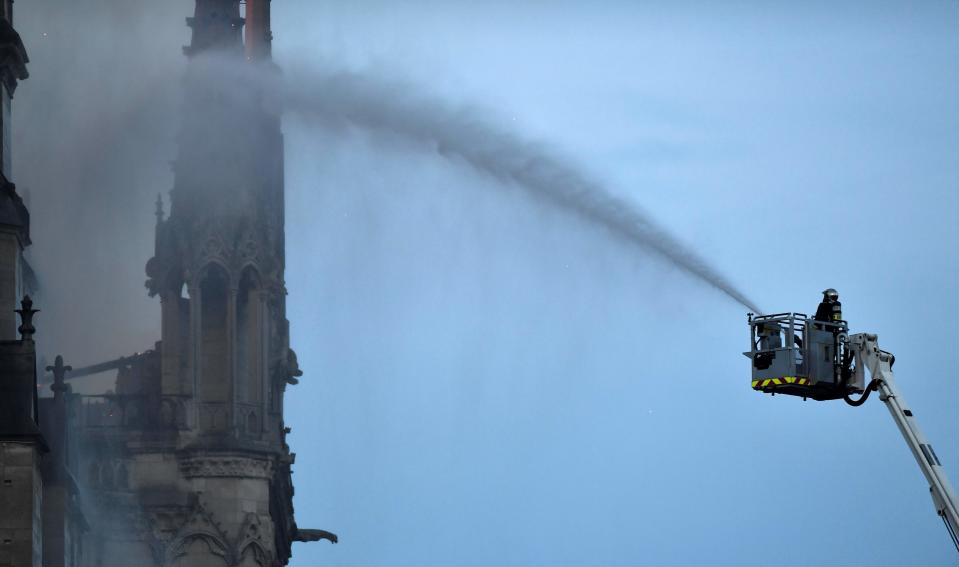 A fire fighter douses flames during a fire at the Notre-Dame de Paris Cathedral on April 15, 2019.