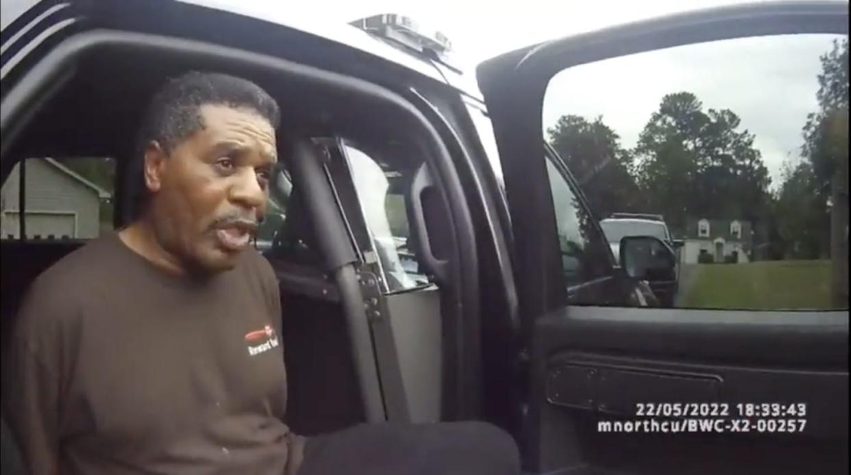 Pastor Michael Jennings sits in a police car while in handcuffs.