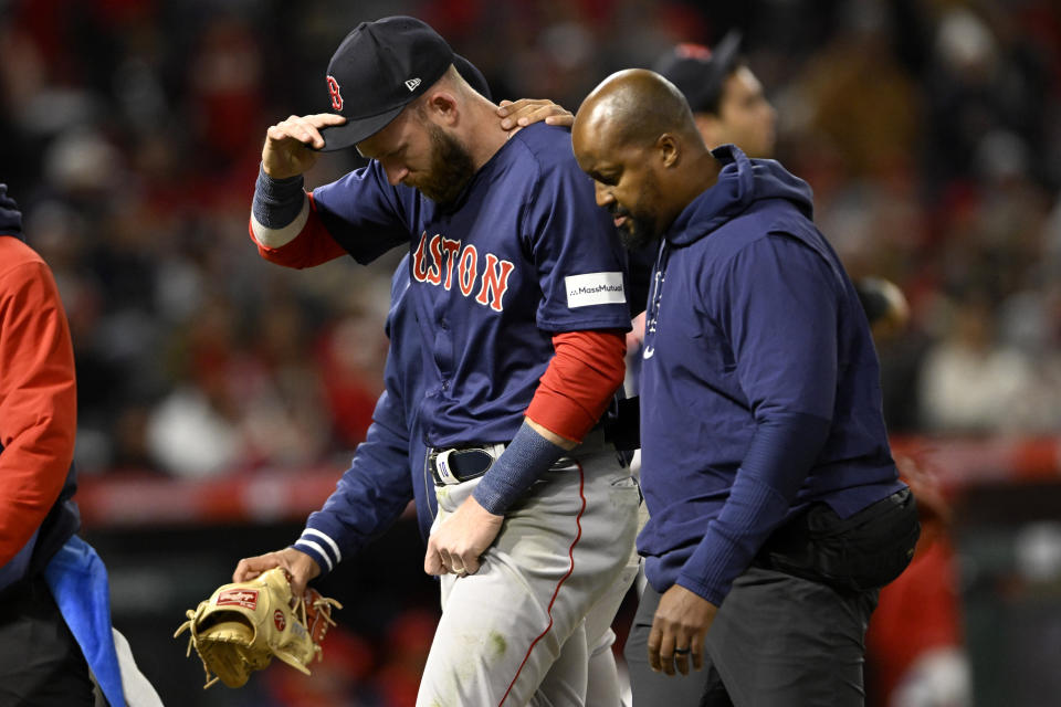 Boston Red Sox shortstop Trevor Story, left, walks off the field after being injured on a single by Los Angeles Angels' Mike Trout during the fourth inning of a baseball game in Anaheim, Calif., Friday, April 5, 2024. (AP Photo/Alex Gallardo)