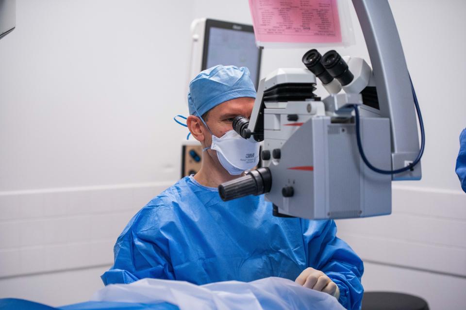 Dr. Douglas Kohl of Eye Associates of Boca Raton looks through an opthalmic microscope before performing cataract surgery on a sedated patient in one of the clinic's operating rooms Monday.