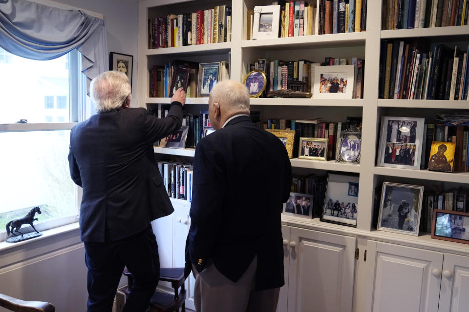 Nick Gage, left, selects a book from his library while talking with his longtime friend Nicholas Basbanes, Wednesday, May 8, 2024, in Grafton, Mass. Authors and retired newspaper journalists Gage and Basbanes decided to sue ChatGPT-maker OpenAI and its business partner Microsoft when they found out that ChatGPT might be stealing and repurposing a lifetime of their work. (AP Photo/Charles Krupa)