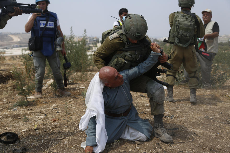 Israeli soldiers detain a Palestinian during a protest against expansion of Israeli settlements in the village of Shufa in the West Bank, Tuesday, Sep. 1, 2020.(AP Photo/Majdi Mohammed)