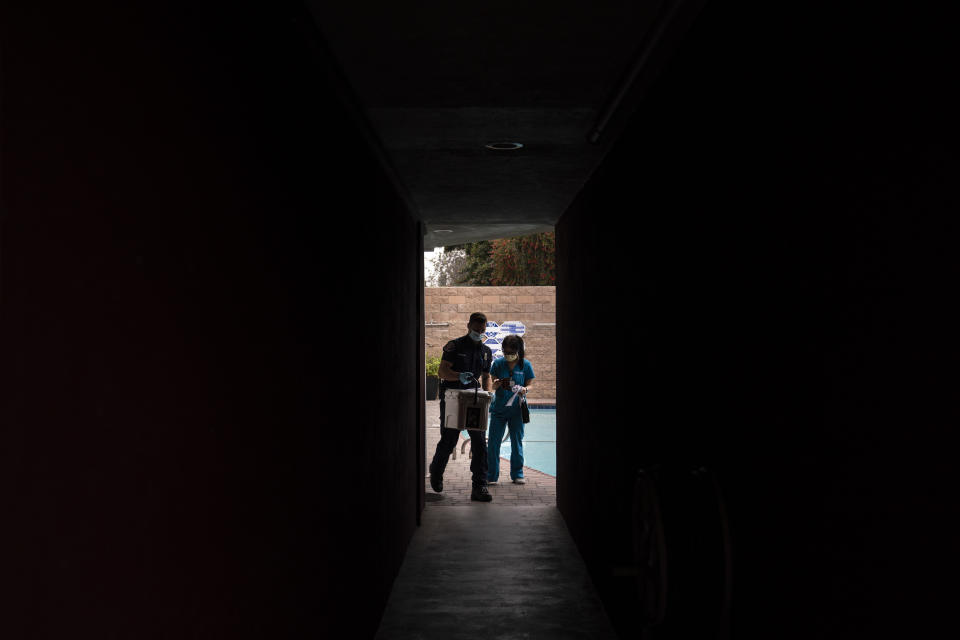 Pharmacist Stella Kim, right, and Torrance firefighter Trevor Borello leave an apartment building after administering the Pfizer COVID-19 vaccine to two sisters who have muscular dystrophy, Wednesday, May 12, 2021, in Torrance, Calif. Teamed up with Torrance Fire Department, Torrance Memorial Medical Center started inoculating people at home in March, identifying people through a city hotline, county health department, senior centers and doctor's offices, said Mei Tsai, the pharmacist who coordinates the program. (AP Photo/Jae C. Hong)