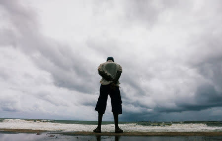 A man looks at the rough sea as rainy clouds gather above during the monsoon period in Colombo, Sri Lanka May 21, 2018. REUTERS/Dinuka Liyanawatte