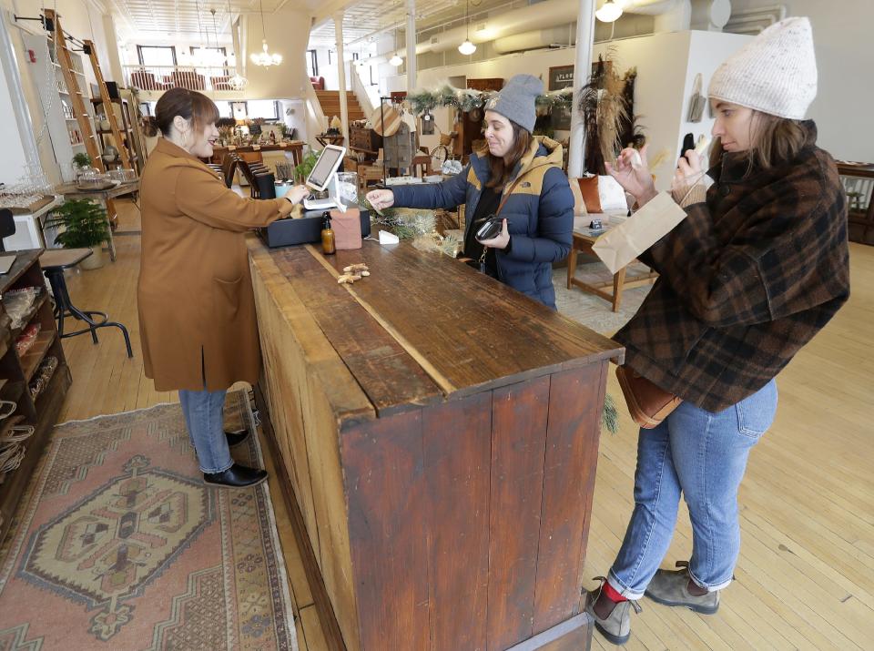 Managing director of the Elsewhere collection, Jessie Tadder, left, assists customers Dec. 3, 2021, during the grand opening of Elsewhere Market and Coffee House, 531 N. Main St., in Oshkosh.