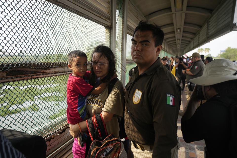 Escorted by Mexican immigration officials, migrants from a group of 50 who were chosen by the Casa Migrante organization, walk across the Puerto Nuevo bridge from Matamoros, Mexico, to be processed by U.S. immigration officials, early Friday, May 12, 2023, the day after U.S. pandemic-related asylum restrictions called Title 42 were lifted. According to Mexican immigration officials, migrants will be organized to cross in groups of 50. (AP Photo/Fernando Llano)