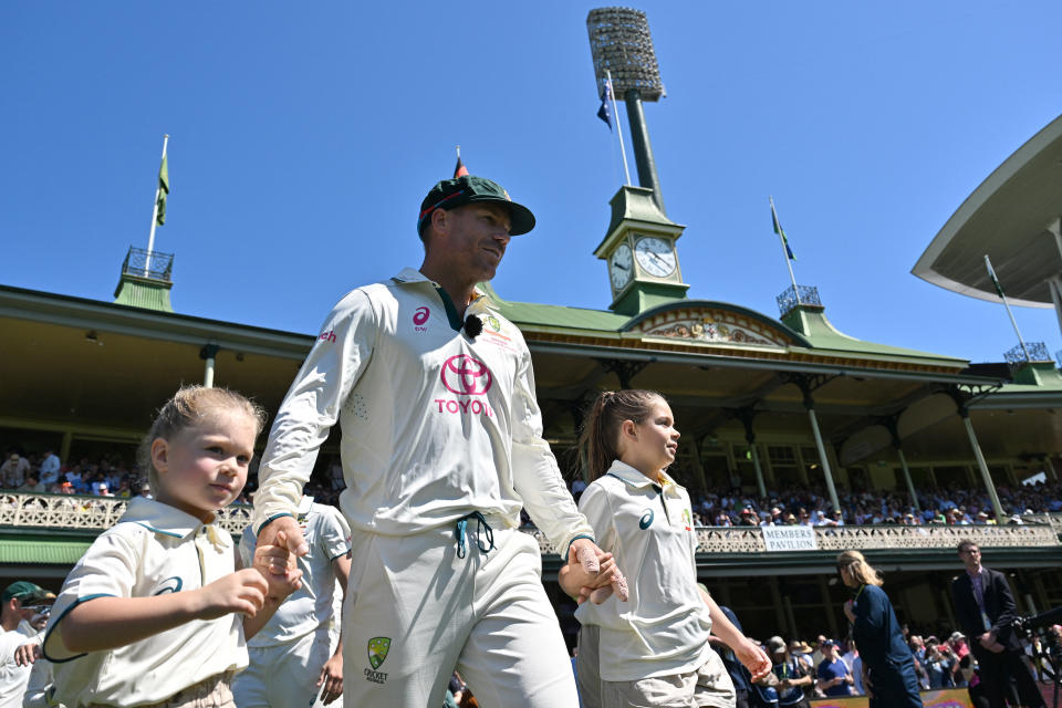 David Warner walks onto the field with his children.