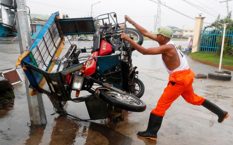 A Filipino villager holds a toppled three wheeled motorcycle - FRANCIS R MALASIG/EPA-EFE/Shutterstock