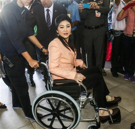 Thailand's Prime Minister Yingluck Shinawatra (C) arrives on a wheelchair at the Royal Police Cadet Academy in Nakorn Pathom province, March 18, 2014. REUTERS/Athit Perawongmetha