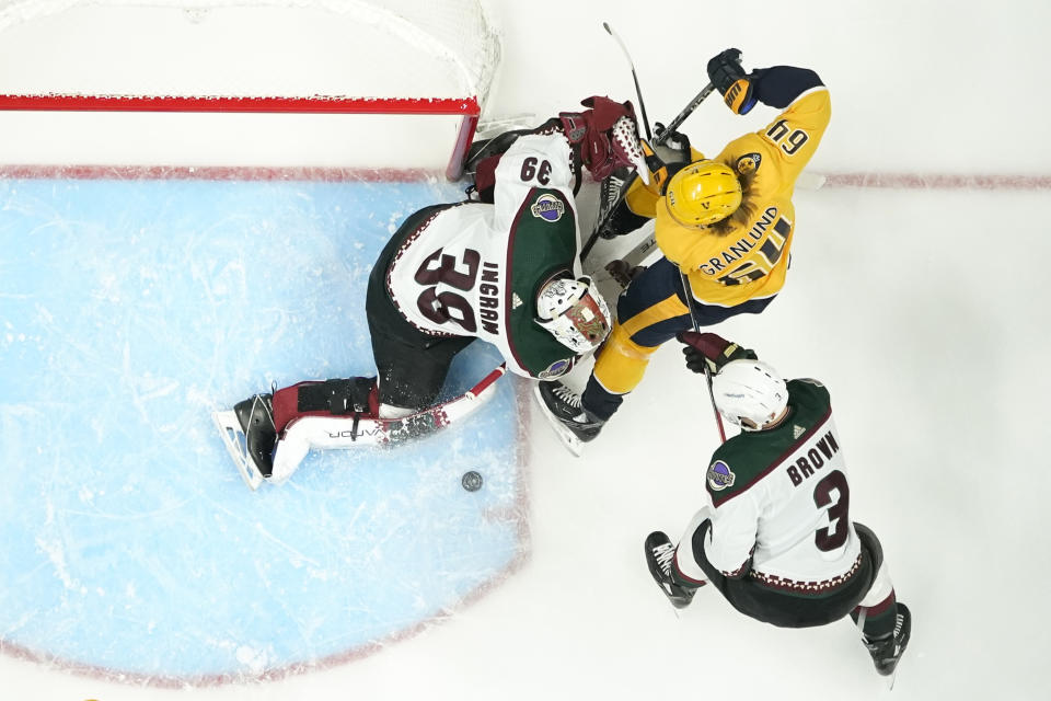 Nashville Predators' Mikael Granlund (64) battles for the puck with Arizona Coyotes goaltender Connor Ingram (39) and Josh Brown (3) in the first period of an NHL hockey game Monday, Nov. 21, 2022, in Nashville, Tenn. (AP Photo/Mark Humphrey)