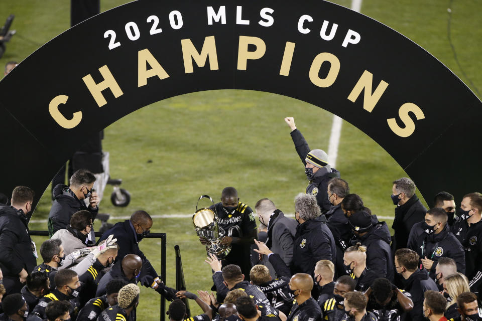 Columbus Crew's Jonathan Mensah, center, carries the trophy on stage after the Crew defeated the Seattle Sounders 3-0 in the MLS Cup championship game Saturday, Dec. 12, 2020, in Columbus, Ohio. (AP Photo/Jay LaPrete)