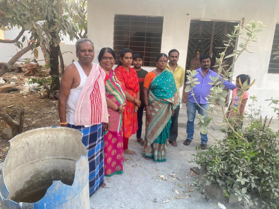 Ramaswamy, his wife and neighbours use a plastic drum to collect water (Stuti Mishra/The Independent)