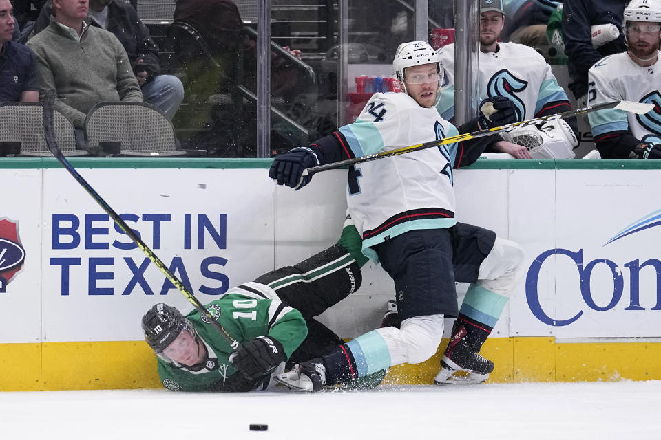 Dallas Stars center Ty Dellandrea (10) and Seattle Kraken defenseman Jamie Oleksiak (24) slam against the boards chasing control of the puck in the first period of an NHL hockey game, Tuesday, March 21, 2023, in Dallas. (AP Photo/Tony Gutierrez)
