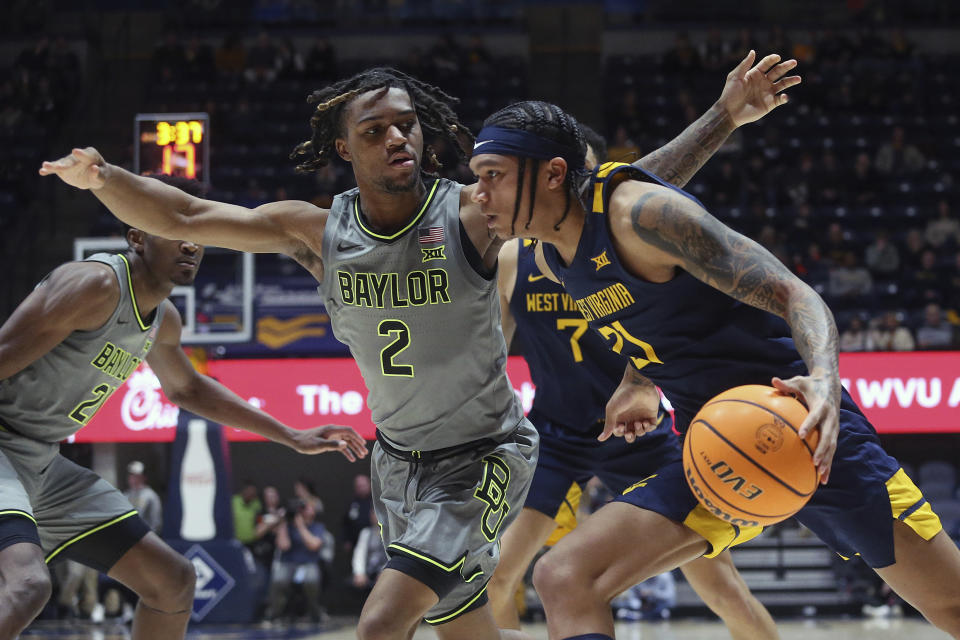 West Virginia guard RaeQuan Battle (21) is defended by Baylor guard Jayden Nunn (2) during the second half of an NCAA college basketball game Saturday, Feb. 17, 2024, in Morgantown, W.Va. (AP Photo/Kathleen Batten)